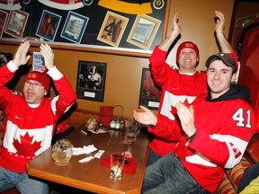 Belleville, Ont. diehard hockey fans, from left, John Keuning and brothers Denis and Mike Schick celebrate at Boston Pizza in Belleville Friday, Feb. 21, 2014 - JEROME LESSARD/The Intelligencer