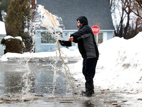 Jack Carrier tries to clear the sewer drains on Hutton Ave. Friday, Feb. 21, 2014. Rain and mild temperatures have caused some flooding.  Tony Caldwell/Ottawa Sun/QMI Agency
