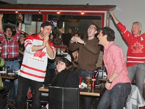 Jeremy Walsh,left, celebrates with his friends Rylend Mulder and Ira Carson and the rest of the packed house at Fanatics Sports Lounge as Team Canada beats the U.S. in the semifinal game Friday.
JULIA MCKAY/KINGSTON WHIG-STANDARD/QMI AGENCY