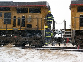 Pincher Creek firefighters, Dan Stumborg (front) and Michael Whittington, inspect a small train fire in the undercarriage of a Union Pacific locomotive stopped in Pincher Station. Greg Cowan photo/QMI Agency.