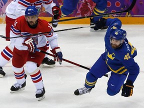 Tomas Plekanec (L) of the Czech Republic trips up Henrik Zetterberg of Sweden during the second period of their men's preliminary round hockey game at the 2014 Sochi Winter Olympic Games, February 12, 2014. (REUTERS/Grigory Dukor)