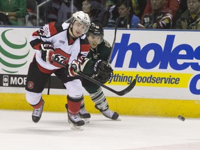 Ottawa 67's forward Brett Gustavsen clears the puck while under pressure from London Knights winger Owen Macdonald during their OHL hockey game at Budweiser Gardens in London, Ont. on Friday. CRAIG GLOVER/The London Free Press/QMI AGENCY