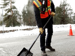 Mayor Don Iveson helps city crews fill potholes along 98 Avenue near 97 Street on Friday. David Bloom/Edmonton Sun