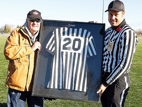 Gord Smith accepts his retired referee's jersey from Andrew Murray during a special ceremony at MAS Park last year. (JEROME LESSARD/The Intelligencer)