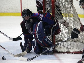 Strathroy Rockets goalie Tynan Lauziere eyes a rolling puck while Chatham Maroons forward and Watford native Kyle Brothers reaches for the disk during GOJHL play Saturday at the West Middlesex Memorial Centre. The Rockets – who won the game 5-4 in overtime – will take on Brothers and the Maroons in Round 1 of the post season.
JACOB ROBINSON/AGE DISPATCH/QMI AGENCY