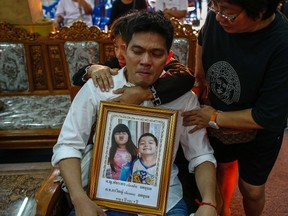 Thayakorn Yosubon, the father of a pair of siblings killed in Sunday's bomb blast near an anti-government protest site, mourns as he hold a photograph of his children during their funeral at a Buddhist temple in Bangkok February 24, 2014.   REUTERS/Athit Perawongmetha