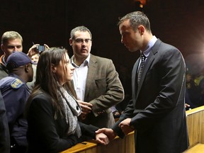 Oscar Pistorius chats with his sister Aimee while holding her hand ahead of court proceedings at the Pretoria Magistrates court on June 4, 2013. (Siphiwe Sibeko/Reuters/Files)