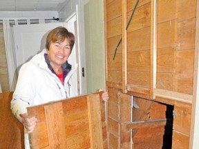 Bev Walkom holds a “trap” door next to the hidden area she and her husband Lloyd found at the back of their downtown Mitchell restaurant BJ’s Ice Cream in January after a frozen pipe caused flooding in the building.  KRISTINE JEAN/MITCHELL ADVOCATE