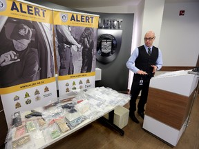 Insp. Darcy Strang displays stacks of $100 bills, various guns with ammunition, brass knuckles, crack cocaine and heroin on Feb 25. PERRY MAH\Edmonton Sun