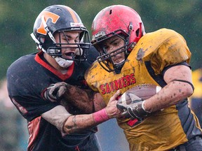 Adam Akila of the Saunders Sabres is tackled by Brandon Murray of Clarke Road Trojans during a wet and muddy football game on Thursday October 31, 2013 (Free Press file photo)