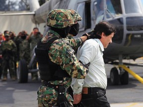 Drugs kingpin Joaquin "Shorty" Guzman (R) is being escorted by soldiers during a presentation at the Navy's airstrip in Mexico City February 22, 2014. (REUTERS/Henry Romero)