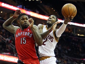 Cavaliers point guard Kyrie Irving (right) goes up for a shot against Raptors forward Amir Johnson in Cleveland last night. (USA Today/photo)