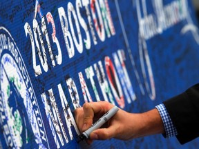 A man signs a memorial for the Boston Marathon bombing victims at the barricade surrounding the finish line in Boston on April 18, 2013. (Brian Snyder/Reuters/Files)