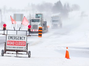 Trucks drive along a closed section of Elginfield Road, east of Highway 4, as snow blows across the road north of London, Ontario on Thursday February 27, 2014.  Many roads were closed due to impaired driving conditions, with emergency crews responding to dozens of calls after high winds and snow hit the region Thursday.
(CRAIG GLOVER/QMI Agency)