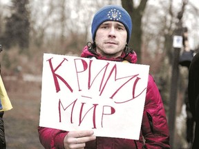 A demonstrator in a European Union toque holds a placard reading ?Peace in Crimea? in front of the Ukrainian parliament during a rally in Kiev on Friday after dozens of pro-Russian gunmen in combat fatigues seized parliament and government buildings in Crimea. (Bulent Kilic/AFP photo)