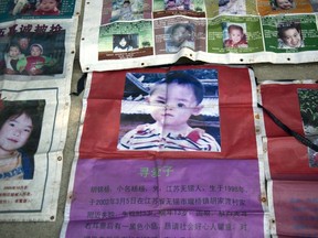 This picture taken on October 23, 2013 shows pictures of missing children displayed by Ye Jinshou, on the streets of Fuzhou on China's east coast Fujian province, helping other parents search for their children.  AFP PHOTO/ED JONES