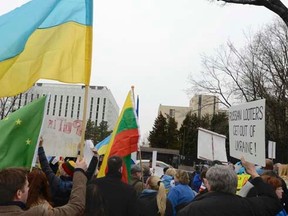 Protesters, one holding up the national Ukrainian flag, gather to demonstrate against Russia's military intervention in Crimea, in front of the Russian Embassy (background) in Washington March 2, 2014.  REUTERS/Mike Theiler