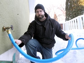 Ryan Black has had to use a hose to get water from a neighbour's house in Winnipeg, Man. Wednesday February 26, 2014. Black has been without water for a month due to frozen pipes. The city is now offering city pool facilities for those who want to take showers, as well as more hoses like this. (Brian Donogh/Winnipeg Sun/QMI Agency)