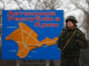 A Russian serviceman stands on duty near a map of the Crimea region near the city of Kerch March 4, 2014. REUTERS/Thomas Peter