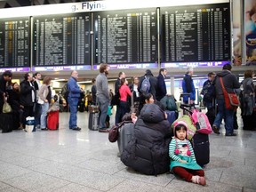A girl sits on the floor in front of a queue at the departure area at the Fraport airport in Frankfurt January 21, 2013. REUTERS/Lisi Niesner