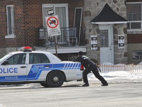 A Montreal police officer has his gun drawn near a row of townhomes where two suspects barricaded themselves inside a unit on March 4, 2014 in Montreal. (SYLVAIN DENIS/QMI Agency)