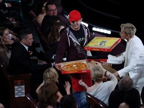 Show host Ellen DeGeneres (R) delivers pizza to the audience as actors Brad Pitt and Angelina Jolie (L) look on at the 86th Academy Awards in Hollywood, California March 2, 2014.  REUTERS/Lucy Nicholson