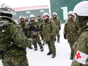 Some of the 300 soldiers from 1st Battalion, The Royal Canadian Regiment based out of CFB Petawawa who participate in Exercise Cold Royal in Loch-Sloy Business Park at Picton, Ont. Airport this week gather near World-War-2-era buildings during urban patrol training Tuesday, March 4, 2014. - JEROME LESSARD/The Intelligencer/QMI Agency