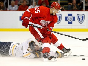 Cory Emmerton of the Detroit Red Wings is tripped up by Thomas Vanek of the Buffalo Sabres in the second period at Joe Louis Arena on October 2, 2013.   Gregory Shamus/Getty Images/AFP