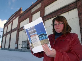 Elgin County Railway Museum manager Dawn Miskelly looks over architect's report detailing restoration of the museum's historic building behind.