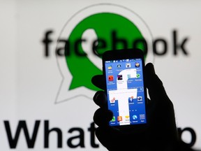 An illustration photo shows a man holding a smart phone with a Facebook logo as its screen wallpaper in front of a WhatsApp messenger logo, in Zenica February 20, 2014. (REUTERS/Dado Ruvic)