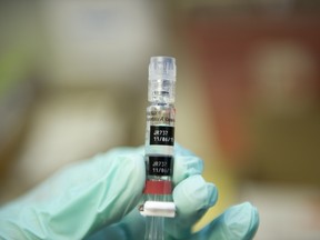 A nurse loads a syringe with a vaccine.