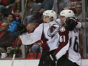 Andre Benoit #61 of the Colorado Avalanche scores the game winning goal in overtime and celebrates with teammate Nathan MacKinnon #29 during the game against the Detroit Red Wings at Joe Louis Arena on March 6, 2014 in Detroit, Michigan. The Avalanche defeated the Wings 3-2 in overtime.  Leon Halip/Getty Images/AFP