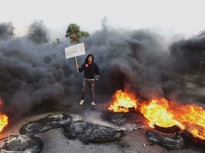 A man holds a sign which reads, "Not extendable" amid smoke and fire after angry protesters set tires on fire during a demonstration against the General National Congress (GNC) in Benghazi. 
REUTERS/Esam Omran Al-Fetori