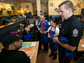 Cst. Ryan May, along with special Olympians Nino and Tavish Tailor, sell a t-shirt to Julian Shorty and Susan Fong during Cops and Crepes at Cora Breakfast and Lunch in Edmonton, Alta., on Saturday, March 8, 2014. Codie McLachlan/Edmonton Sun/QMI Agency