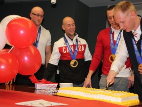 Brad Jacobs (right) and his rink, winners of the gold medal for men's curling at 2014 Sochi Winter Olympics, cuts a cake at Ontario Lottery and Gaming headquarters in Sault Ste. Marie, Ont., on Thursday, Feb. 27, 2014. Team member E.J. Harnden is an instant brand manager at OLG. (BRIAN KELLY/THE SAULT STAR/QMI AGENCY)