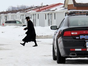A member of the ultra-orthodox Lev Tahor sect walks across the roadway leading into their enclave at Spurgeon's Villa, north of Chatham, Ont., while Chatham-Kent police keep watch over the community on Wednesday, March 5, 2014. (VICKI GOUGH/QMI Agency)