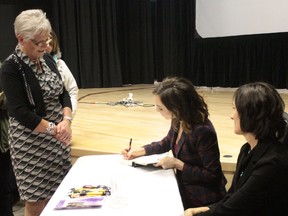 Amanda Lindhout signs a copy of her book A House in the Sky, while mom Lorinda Stewart looks on after the two spoke to a packed house at the Eleanor Pickup Arts Centre on Mar. 8. The women were brought to town by the Pembina Crisis Connection Society.