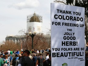 A man holds a sign referring to Colorado legalizing marijuana with the state capitol dome in the background at the 4/20 marijuana holiday in Civic Center Park in downtown Denver in this April 20, 2013 file photo.  REUTERS/Rick Wilking/Files