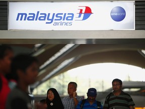 People walk under a Malaysia Airlines sign at Kuala Lumpur International Airport in Sepang March 8, 2014. REUTERS/Samsul Said