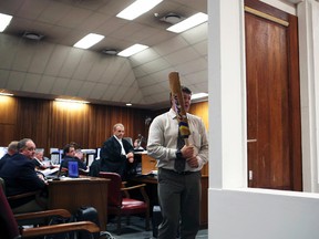 A policeman demonstrates the effect of hitting of a bathroom door with a cricket bat during the trial of South African athlete Oscar Pistorius in the North Gauteng High Court in Pretoria, March 12, 2014.  (ALEXANDER JOE/Reuters/Pool)