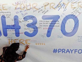 A woman writes a message of support and hope for the passengers of the missing Malaysia Airlines MH370 on a banner at Kuala Lumpur International Airport March 12, 2014.    REUTERS/Damir Sagolj