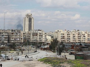 Smoke rises as civilians walk at the Karaj al-Hajez crossing, a passageway separating Aleppo's Bustan al-Qasr, which is under the rebels' control and Al-Masharqa neighbourhood, an area controlled by the regime March 13, 2014. REUTERS/Sultan Ketaz