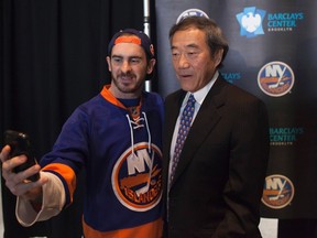 Hockey fan Tim Watson of New York takes a cell phone photo of himself with New York Islanders owner Charles Wang October 24, 2012. (REUTERS/Andrew Kelly)
