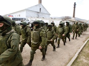 Armed men, believed to be Russian servicemen, walk outside a Ukrainian military base in Perevalnoye, near the Crimean city of Simferopol, March 14, 2014. Russia shipped more troops and armour into Crimea on Friday and repeated its threat to invade other parts of Ukraine, showing no sign of listening to Western pleas to back off from the worst confrontation since the Cold War.  REUTERS/Vasily Fedosenko