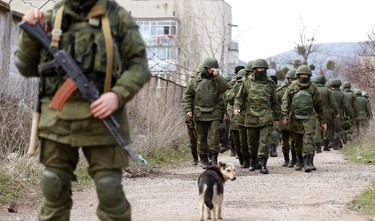 Armed men, believed to be Russian servicemen, walk outside a Ukrainian military base in Perevalnoye, near the Crimean city of Simferopol, March 14, 2014. A Russian warship unloaded trucks, troops and at least one armoured personnel carrier at a bay near Sevastopol in Crimea on Friday morning, as Moscow continued to build up its forces on the Ukrainian peninsula.  REUTERS/Vasily Fedosenko (UKRAINE - Tags: POLITICS MILITARY)