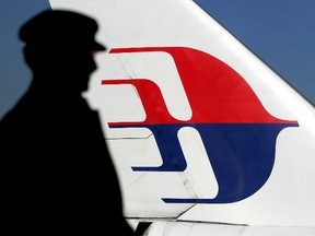 A file photo taken on July 5, 2005 shows a man silhouetted against a Malaysian Airlines plane tail as he looks out through a window at Sydney International Airport. AFP PHOTO/Greg WOOD/FILES