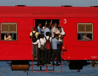 People hang onto a crowded local passenger train as they travel to Colombo March 11, 2014. REUTERS/Dinuka Liyanawatte