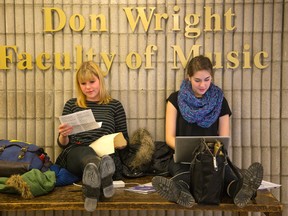 Music students Emily Bird of Toronto and Kelsea Crowe of London get some reading in while perched on a table at the Don Wright faculty of music at Western University in London. (MIKE HENSEN, The London Free Press)