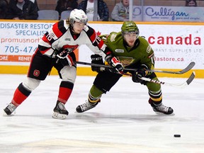 Ottawa 67's forward Connor Graham, left, and North Bay Battalion forward Mike Baird battle for a loose puck Sunday during a March 16, 2014 OHL game at Memorial Gardens in North Bay, Ont. The Battalion set a franchise record with a 12-1 win.GORD YOUNG/The Nugget/QMI Agency