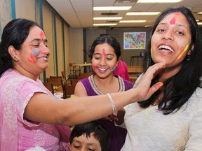 Subha Mukherjee, left to right, Nandini Mukherjee, Navita Kumari and five-year old Sidd Kumar, get the colourful powders ready to welcome people to the Hindu Cultural Temple of Kingston Holi celebrations on Saturday. Julia McKay/The Whig-Standard